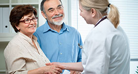 Doctor shaking hands with older couple