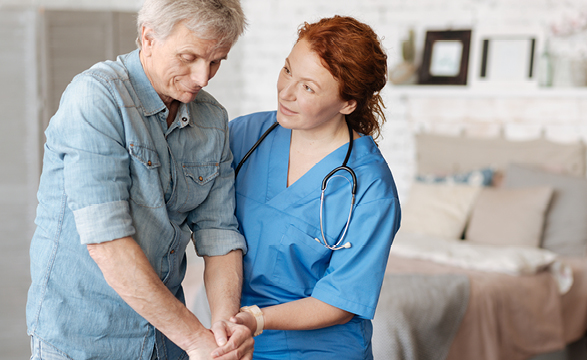 a female nurse helping an older man standup