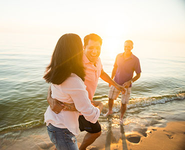 Three people on beach at sunset