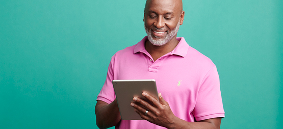 man in pink shirt using a tablet