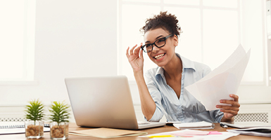smiling woman with papers and a laptop