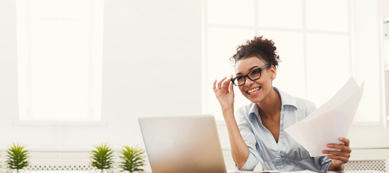 woman smiling with laptop and holding papers