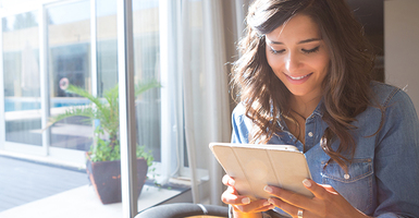 Woman reading tablet by window