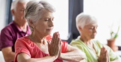 Elderly group of individuals in yoga class with folded hands